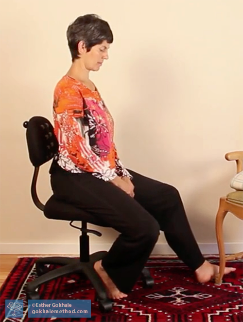 Esther Gokhale sitting on her Pain-Freechair, side view, legs externally rotated.
