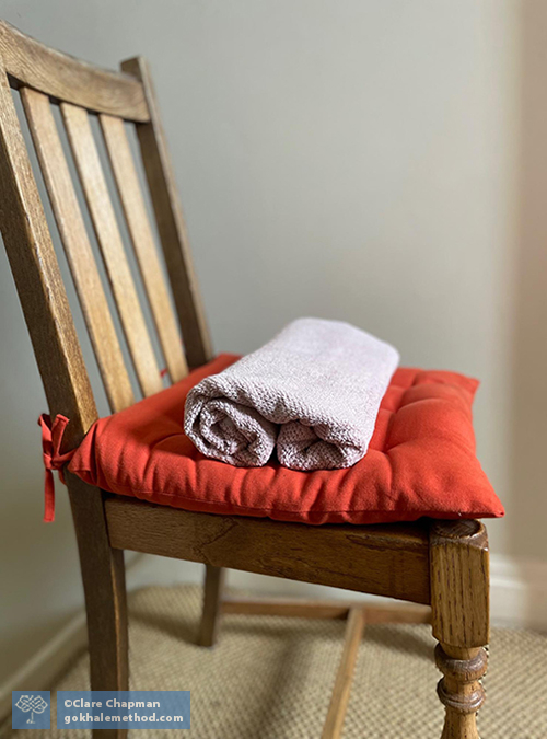 Photo of a rolled towel wedge on a chair.