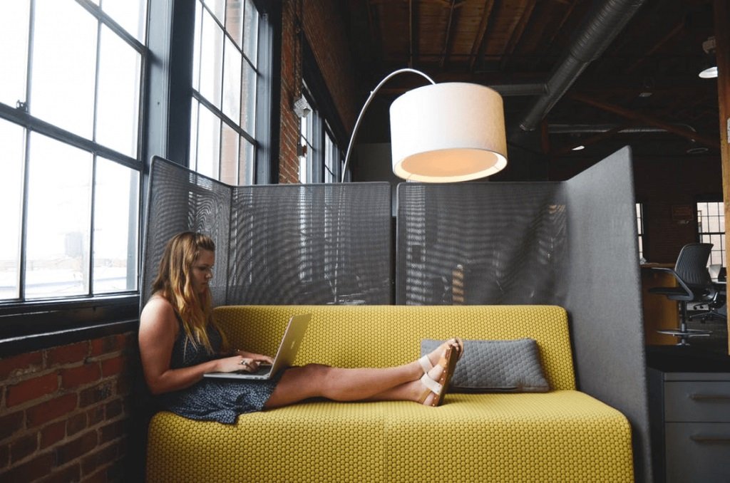 Woman legs up on sofa slouched with laptop.