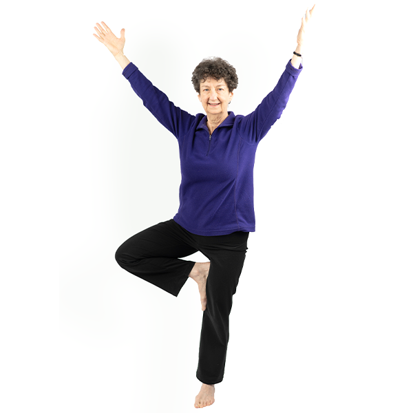 Photo of a woman doing tree pose with a healthy J-spine posture and smiling.