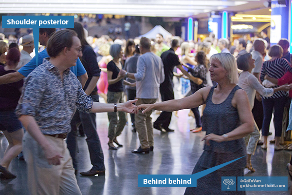 Man and woman dancing together, with other couples around.