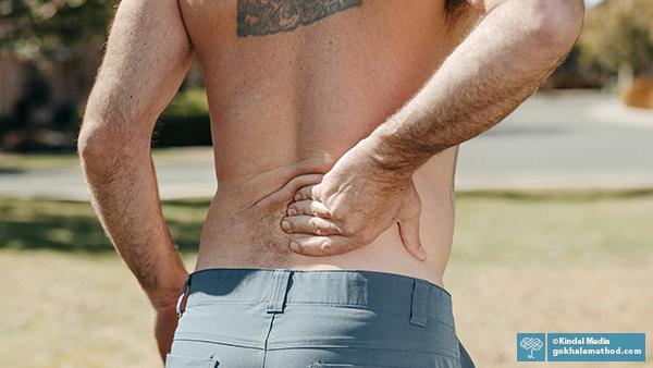 Photo of man holding his painful lower back, back view.