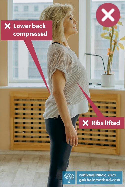 Woman straining to stand up straight with chest lifted.
