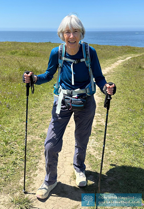 Christine Hageline standing outdoors hiking with walking poles.