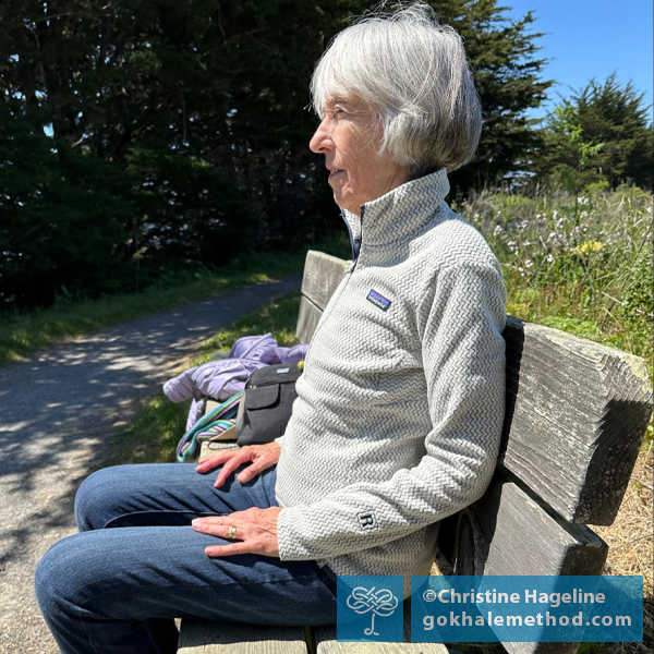 Christine Hageline stretchsitting on a bench outdoors.