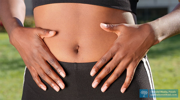 Woman with healthy posture resting her hands on her lower belly.