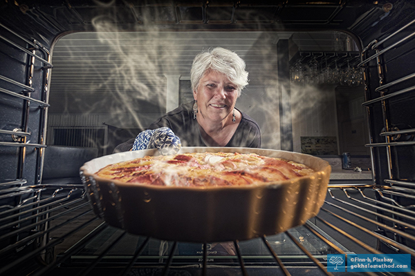 Woman retrieving a hot flan dish from a low oven shelf