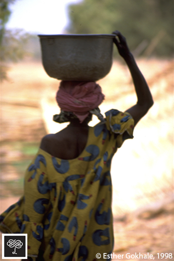 Woman head loading water holding basin, Burkina Faso, back view