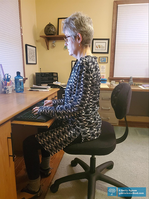 Photo of Emily Agnew stacksitting on her Gokhale Pain-Free Chair at her computer