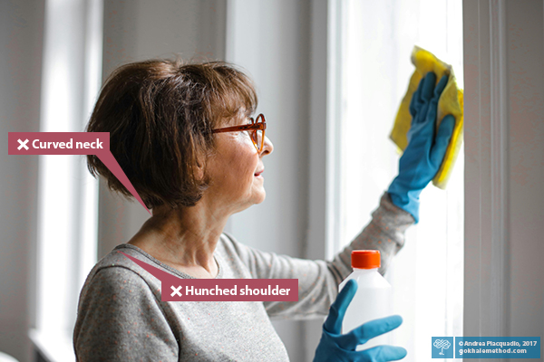 Woman cleaning a window with hunched shoulders and a curved neck.