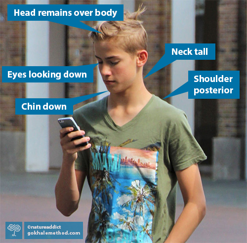 Teenage boy with tall neck looking down at phone.