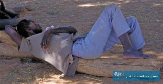 African villager comfortably reclined on a hard log.