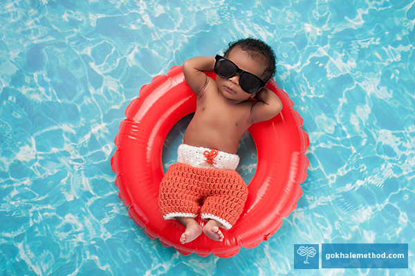 Photo of reclining baby floating in a ring and wearing shades.