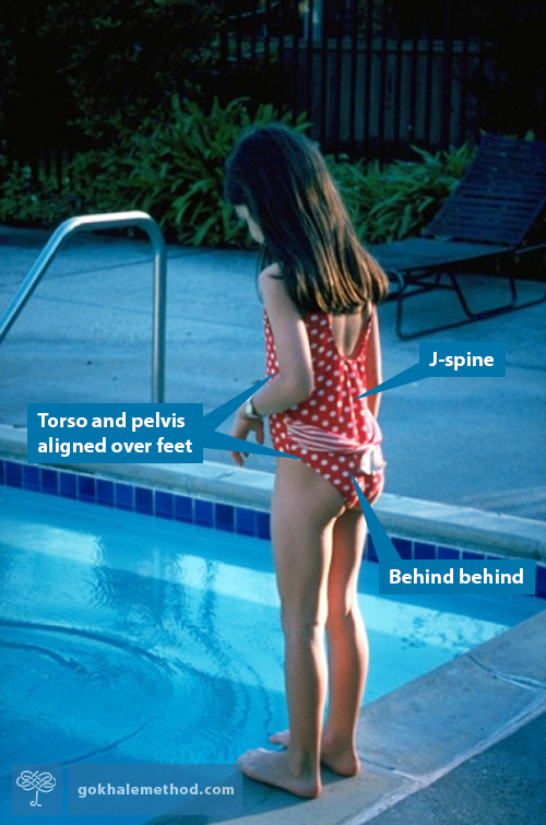 Girl standing upright and relaxed looking into a pool.