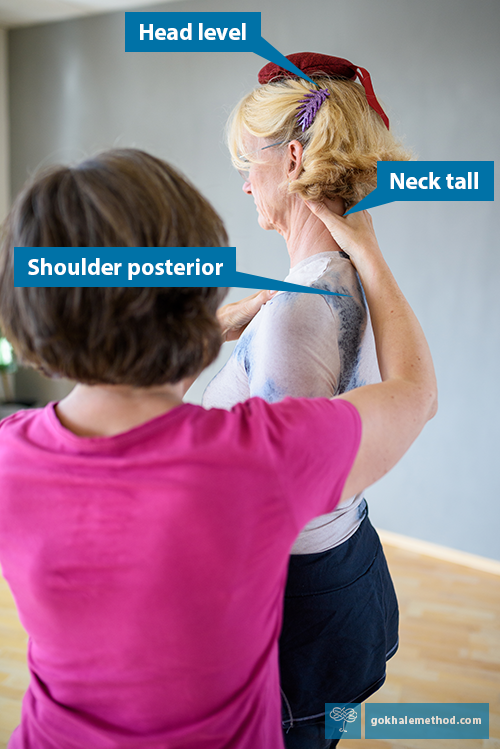 Teacher Julie Johnson helps a student lengthen her neck with a head cushion and hands-on.