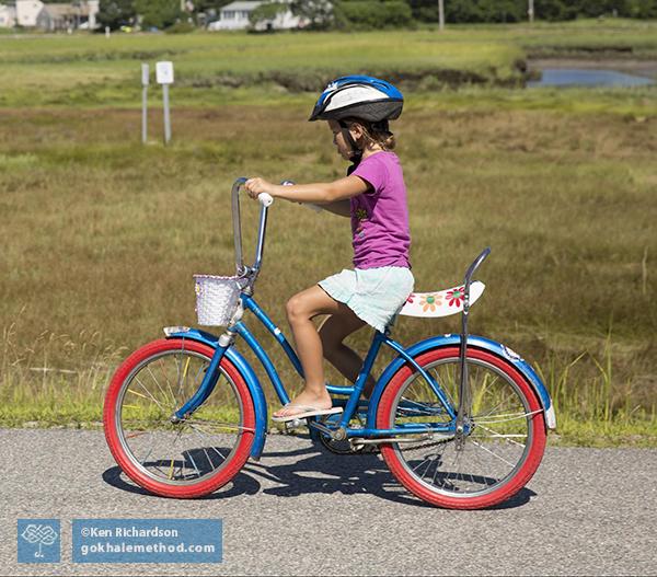 Willa Brown, aged four, riding a bike, sitting upright.