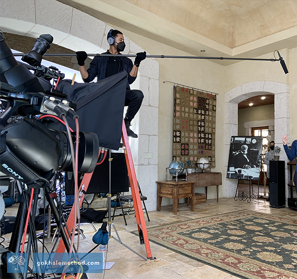 Boom operator Jermaine Battle holding boom pole sitting astride tall ladder. 