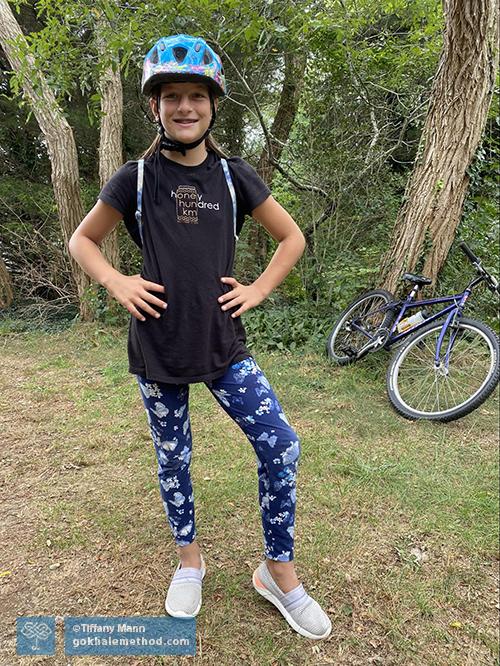 Willa Brown, aged 12, standing, hands on hips, ready to cycle.