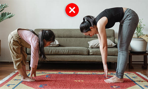 Mother and daughter in standing forward bend, side view, straight legs, rounded back.