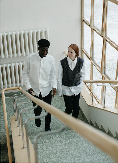 A young man and woman ascending stairs side by side.