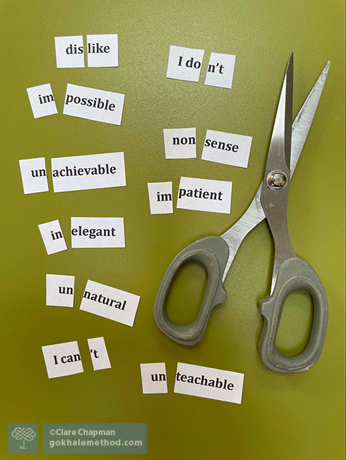 Photo of negative words that have been cut away from their prefixes with scissors.