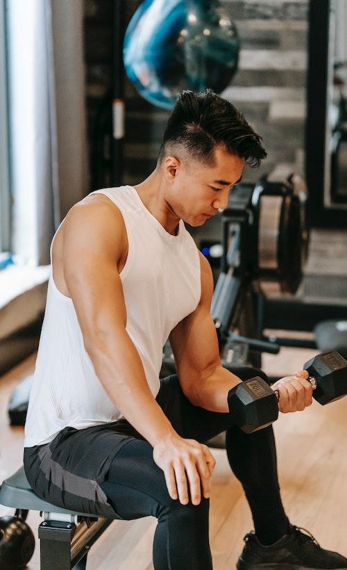 Photo of seated man working bicep with dumbbell.