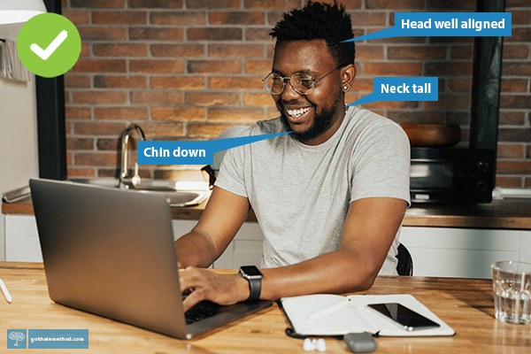 Man wearing glasses at desk using laptop, neck , head, and eyes comfortably angled down.